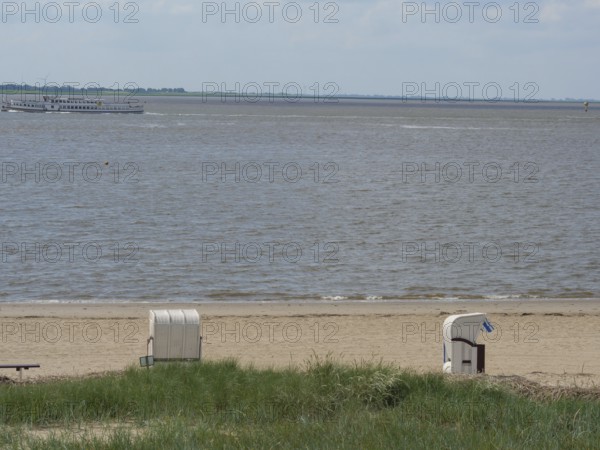Two beach chairs on the beach with a view of the sea and a slightly cloudy sky, bremerhaven, bremen, germany