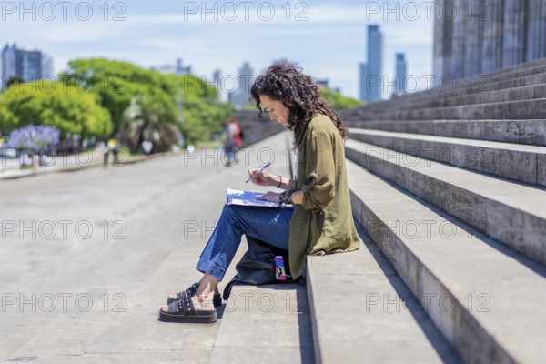Thoughtful woman sketching on the steps of her college