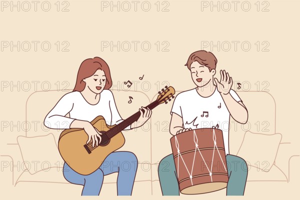 Cheerful friends man and woman playing musical instruments, sitting on sofa and using drum with guitar. Creative guy and girl enjoying playing musical hits during sunday relaxation