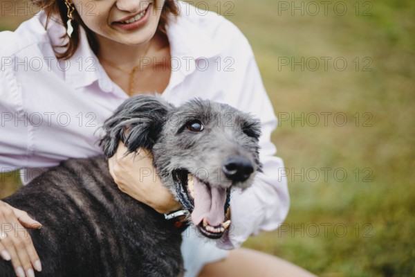 Close-up of a smiling woman with a happy dog outdoors on grass
