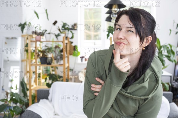 Thoughtful emotions of a woman in her home in a bright modern interior with home plants. Portrait of a dreamy