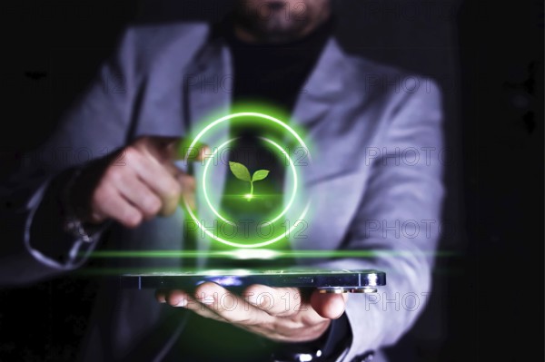Businessman pointing to his cell phone with an icon of growing and protecting plants and the environment.