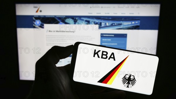 Stuttgart, Germany, 09-17-2023: Person holding cellphone with logo of German federal agency Kraftfahrt-Bundesamt (KBA) on screen in front of webpage. Focus on phone display, Europe