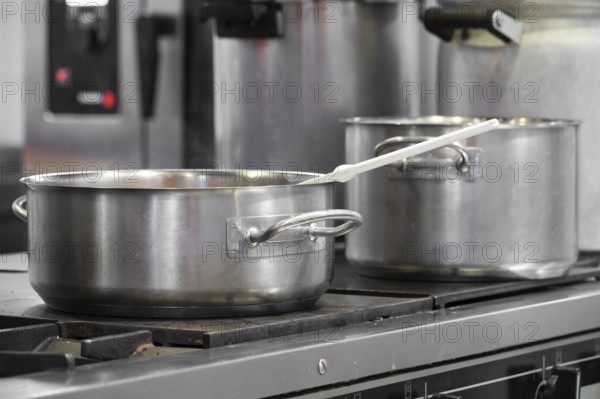 Close up view of casseroles at a commercial kitchen. Preparing and cooking food in a commercial kitchen. Unrecognizable Chefs in the background. graphy
