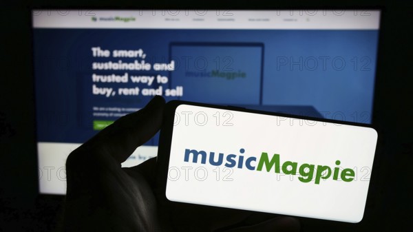 Stuttgart, Germany, 12-07-2023: Person holding smartphone with logo of British e-commerce company MusicMagpie in front of website. Focus on phone display, Europe