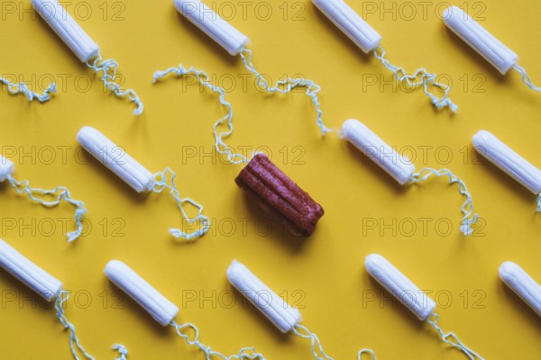 many new clean tampons and one used bloody tampon - period or menstruation flat lay concept with fake blood