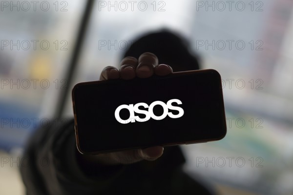Dhaka, Bangladesh 14 Dec 2024:Cellphone with logo of British fashion retail company ASOS plc on screen in front of business website. Focus on center-left of phone display.