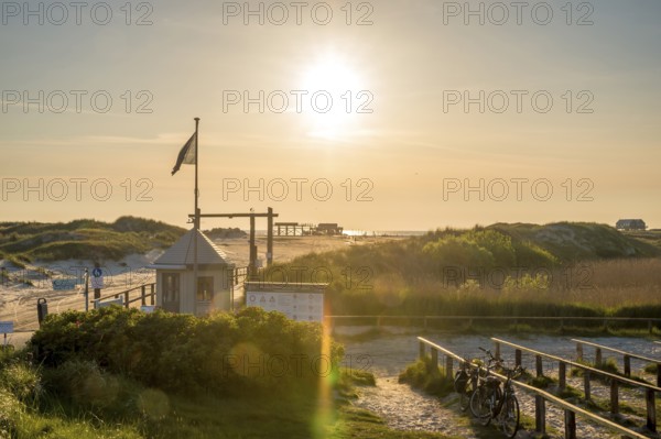 Beach access in the dunes with map house and bicycle stands backlit by the evening sun, St. Peter Ording, Schleswig Holstein, Germany, Europe