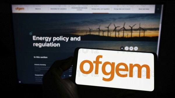 Stuttgart, Germany, 07-15-2022: Person holding mobile phone with logo of Office of Gas and Electricity Markets (Ofgem) on screen in front of web page. Focus on phone display, Europe