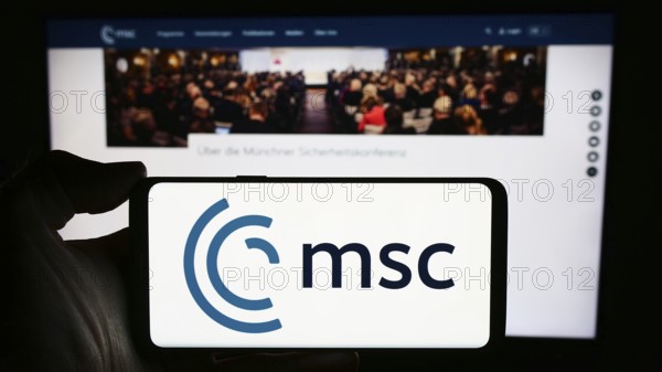Stuttgart, Germany, 03-06-2024: Person holding cellphone with logo of annual event Munich Security Conference (MSC) in front of webpage. Focus on phone display, Europe