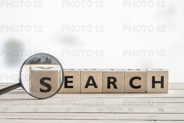 Magnifying glass with the word search on a wooden desk