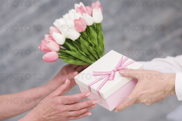 Man s hand giving birthday gift tulip flowers bouquet his wife