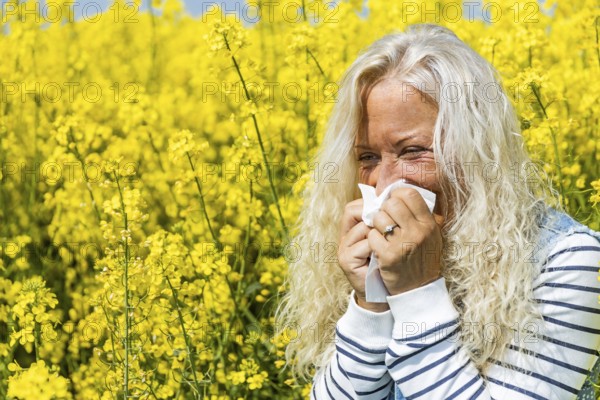 Woman suffers from allergy in a rape field and has to sneeze