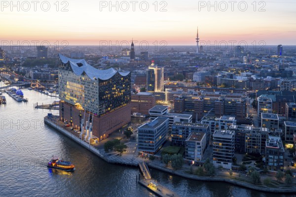 Aerial view of the Elbphilharmonie at sunset with illuminated windows and view over Hamburg, Landungsbrücken and the main church St. Michaelis (Michel), Hamburg, Germany, Europe