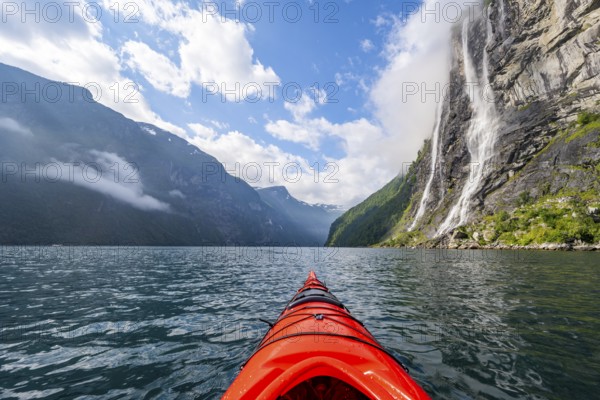Kayak trip on the Geirangerfjord at the waterfall The Seven Sisters, tip of a red kayak in the fjord, atmospheric fjord landscape, first person view, near Geiranger, Møre og Romsdal, Norway, Europe