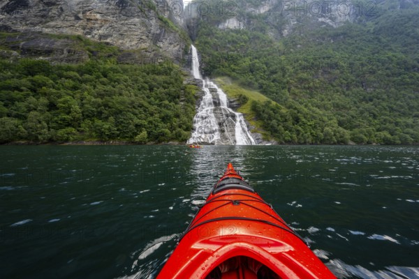 Kayak trip on the Geirangerfjord at the Freier waterfall, tip of a red kayak in the fjord, atmospheric fjord landscape, first person view, near Geiranger, Møre og Romsdal, Norway, Europe