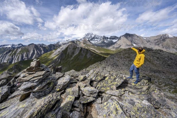 Mountaineer points into the distance, at the summit of Kastenegg, view of picturesque mountain landscape with snow-covered summit of the Großglockner, Wiener Höhenweg, Schober group, Hohe Tauern National Park, Carinthia, Austria, Europe