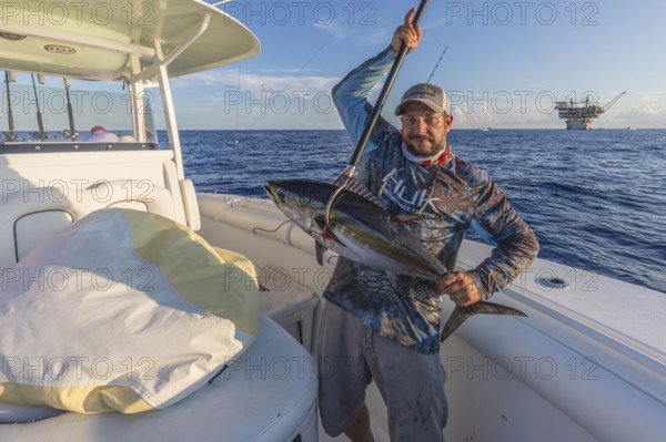 Offshore fisherman showing off his tuna caught near petroleum drilling rigs in the Gulf of Mexico