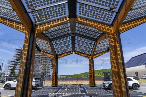 Electric charging station on the site of the former Lohberg colliery in Dinslaken, operated by Fastned, uses electricity from wind power and solar energy, fast-charging columns, with its own solar roof, in the background the 11, 500 square metre solar roof on the colliery's former coal mixing hall, wind farm on the Lohberg slagheap, North Rhine-Westphalia, Germany, Europe