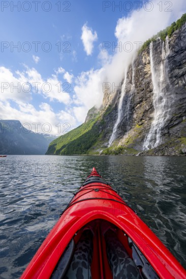 Kayak trip on the Geirangerfjord at the waterfall The Seven Sisters, tip of a red kayak in the fjord, atmospheric fjord landscape, first person view, near Geiranger, Møre og Romsdal, Norway, Europe