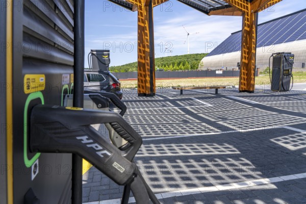Electric charging station on the site of the former Lohberg colliery in Dinslaken, operated by Fastned, uses electricity from wind power and solar energy, fast-charging columns, with its own solar roof, in the background the 11, 500 square metre solar roof on the colliery's former coal mixing hall, wind farm on the Lohberg slagheap, North Rhine-Westphalia, Germany, Europe