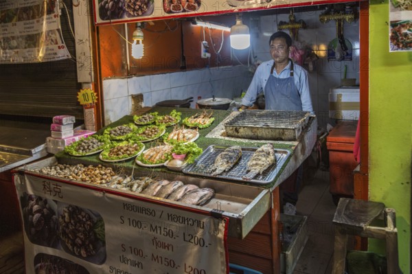 Thai street vendor offers fresh cooked seafood at the night market in downtown Chiang Rai, Thailand, Asia