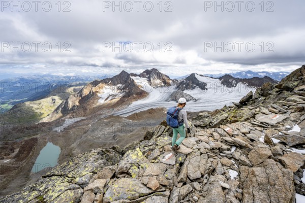 Mountaineer with helmet on a rocky hiking trail, in high mountain landscape, view of blue glacial lakes, mountain peaks Königshofspitz and Hofmannspitze with glacier of the Übeltalferner, Stubai Alps, South Tyrol, Italy, Europe