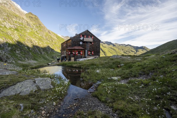 Mountain hut Elberfelderhütte with small lake and cotton grass, in the morning light, in the upper Gössnitz valley, Wiener Höhenweg, Schober group, Hohe Tauern National Park, Carinthia, Austria, Europe