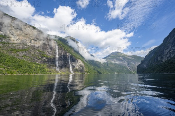 Atmospheric fjord landscape with waterfall The Seven Sisters, Geirangerfjord with reflection, Møre og Romsdal, Norway, Europe