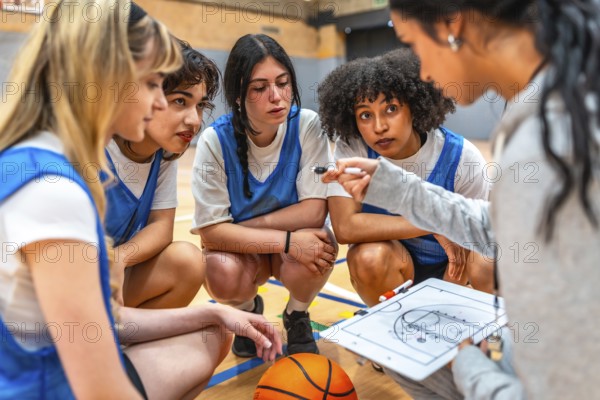 Basketball coach explaining game strategy to her young female athletes using whiteboard and marker in a gym