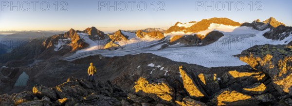 Mountaineers in front of a picturesque high mountain landscape at sunrise with alpenglow, blue glacial lakes, glaciers and rocky mountain peaks in the morning light, view at the Becher on mountain peaks Königshofspitz and Sonklarspitze and Schwarzwandspitz with glacier Übeltalferner, Stubai Alps, South Tyrol, Italy, Europe