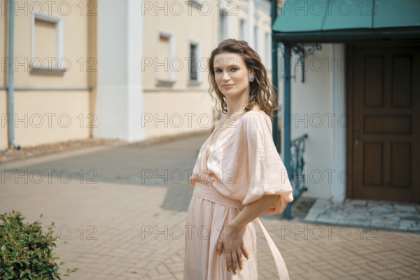 Confidence shines through as a woman poses in a charming urban setting with soft sunlight