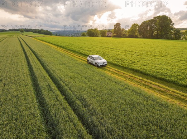 Car on a rural road with fields and rooftops under a cloudy sky, Deer E- CarSharing, Renault Megane electric car, Calw, Black Forest, Germany, Europe