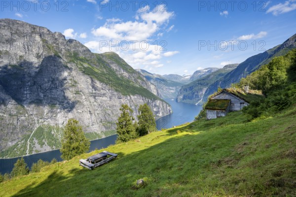 Blomberg Gård, historic mountain farm with grass roof on a steep mountainside above the Geirangerfjord, view of idyllic fjord landscape, near Geiranger, Møre og Romsdal, Norway, Europe