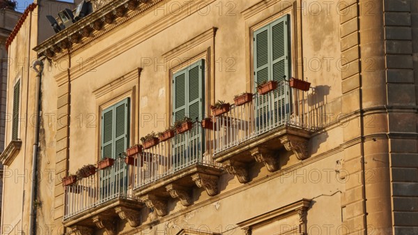 Detail of the façade of a historic building in warm sunlight with balconies, Ortigia Island, Isola di Ortigia, Historic Centre, Syracuse, Sicily, Italy, Europe