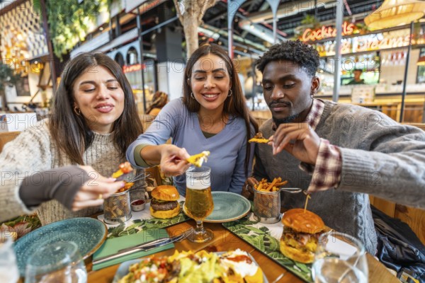 Three happy friends enjoying a meal together, sharing nachos, burgers, and fries at a restaurant table