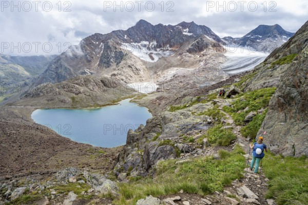 Mountaineer on hiking trail in dramatic high mountain landscape, view of mountains with mountain lake Vogelhüttensee and glacier Übeltalferner, Stubai Alps, South Tyrol, Italy, Europe