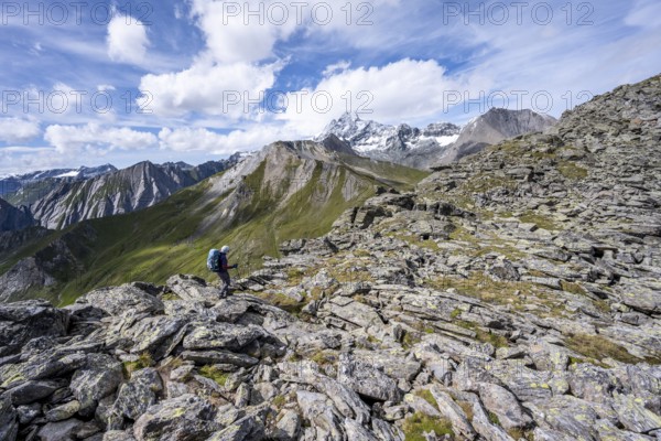 Mountaineer in boulder terrain, at the summit of Kastenegg, view of picturesque mountain landscape with snow-covered summit of the Großglockner, Vienna High Trail, Schober Group, Hohe Tauern National Park, Carinthia, Austria, Europe