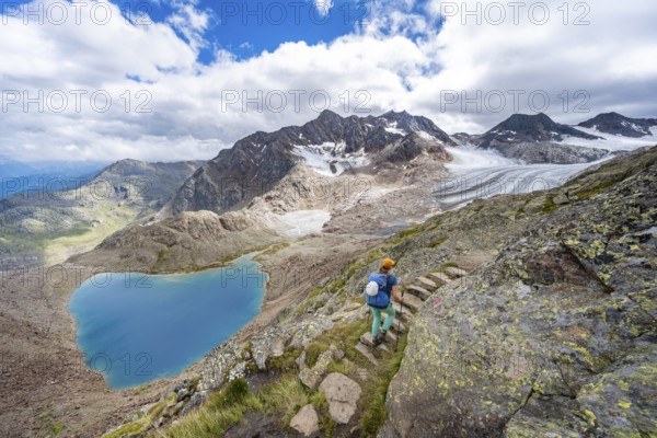 Mountaineer on hiking trail in front of dramatic high mountain landscape, view of mountain lake Vogelhüttensee and glacier Übeltalferner, Stubai Alps, South Tyrol, Italy, Europe