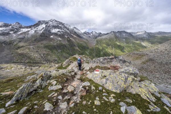 Mountaineer on a hiking trail, rocky mountain landscape, mountain peak Roter Knopf with fresh snow in summer, descent from the Hornscharte on the Wiener Höhenweg, Schober group, Hohe Tauern National Park, Carinthia, Austria, Europe