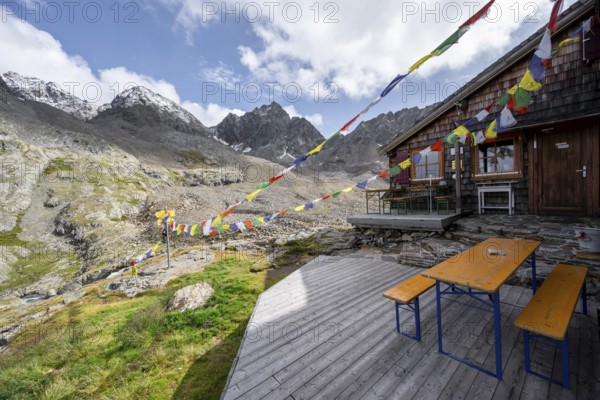 Colourful prayer flags, terrace at a mountain hut, mountain hut Adolf-Nossberger-Hütte, mountain landscape with rocky mountain peaks, in the background summit of Petzeck and Kruckelkopf, Schober group, Hohe Tauern National Park, Carinthia, Austria, Europe