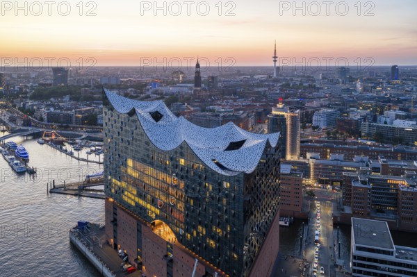 Aerial view of the Elbphilharmonie at sunset with illuminated windows and view over Hamburg, Landungsbrücken and the main church St. Michaelis (Michel), Hamburg, Germany, Europe