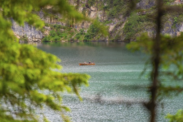 A small boat on a spacious, quiet lake surrounded by lush trees, Pragser Wildsee, South Tyrol, Dolomites, Italy, Europe