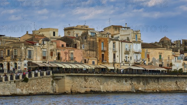 Coastal view with a mix of old buildings and modern terraces along the waterfront, boat trip around the island of Ortigia, Isola di Ortigia, Syracuse, Sicily, Italy, Europe