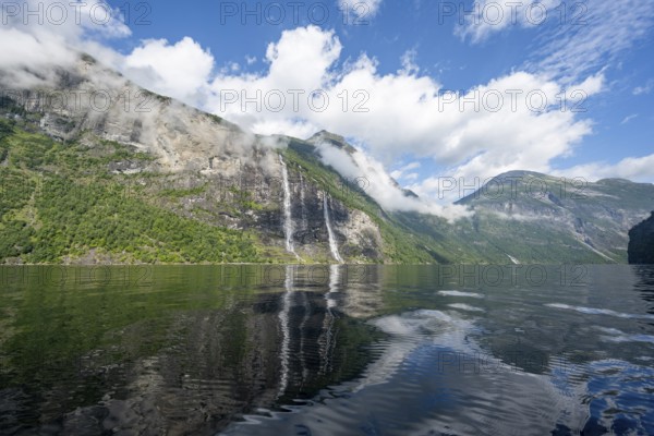 Atmospheric fjord landscape with waterfall The Seven Sisters, Geirangerfjord with reflection, Møre og Romsdal, Norway, Europe