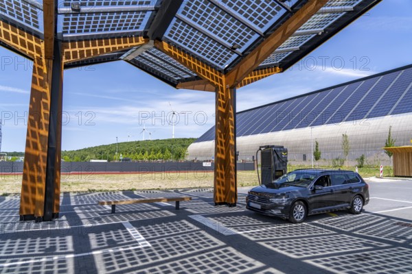 Electric charging station on the site of the former Lohberg colliery in Dinslaken, operated by Fastned, uses electricity from wind power and solar energy, fast-charging columns, with its own solar roof, in the background the 11, 500 square metre solar roof on the colliery's former coal mixing hall, wind farm on the Lohberg slagheap, North Rhine-Westphalia, Germany, Europe