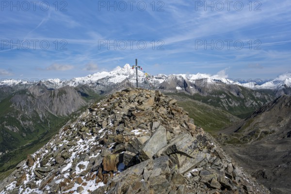 Böses Weibl summit with summit cross and colourful prayer flags, view of picturesque mountain landscape with snow-covered summit of the Großglockner, Wiener Höhenweg, Schober group, Hohe Tauern National Park, Carinthia, Austria, Europe