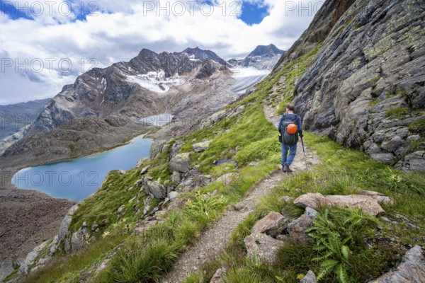 Mountaineer on hiking trail in dramatic high mountain landscape, view of mountains with mountain lake Vogelhüttensee and glacier Übeltalferner, Stubai Alps, South Tyrol, Italy, Europe