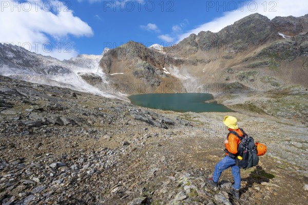 Mountaineer in front of mountain landscape with limestone rocks between granite mountains, mountain lake Hinterer Senner Egetsee and mountain peak of the Moarer Weißen, Seven Lakes Hike, Stubai Alps, near Ridnaun, South Tyrol, Italy, Europe