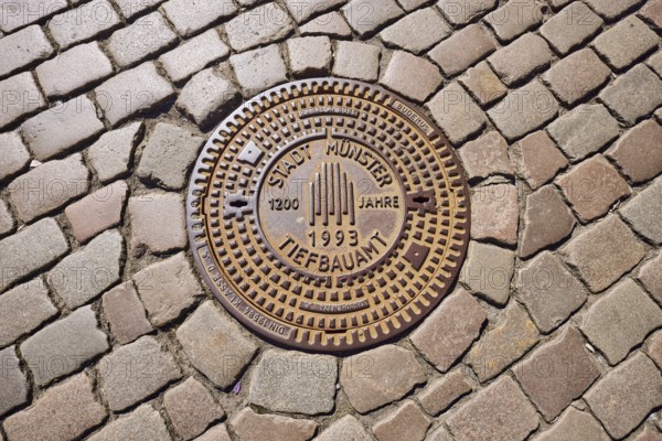 Manhole cover, city of Münster civil engineering, 1200 years 1993, cobblestones, Münster, Münsterland, independent city, North Rhine-Westphalia, Germany, Europe
